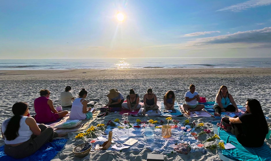 Mujeres en la playa al amanecer en un círculo de meditación
